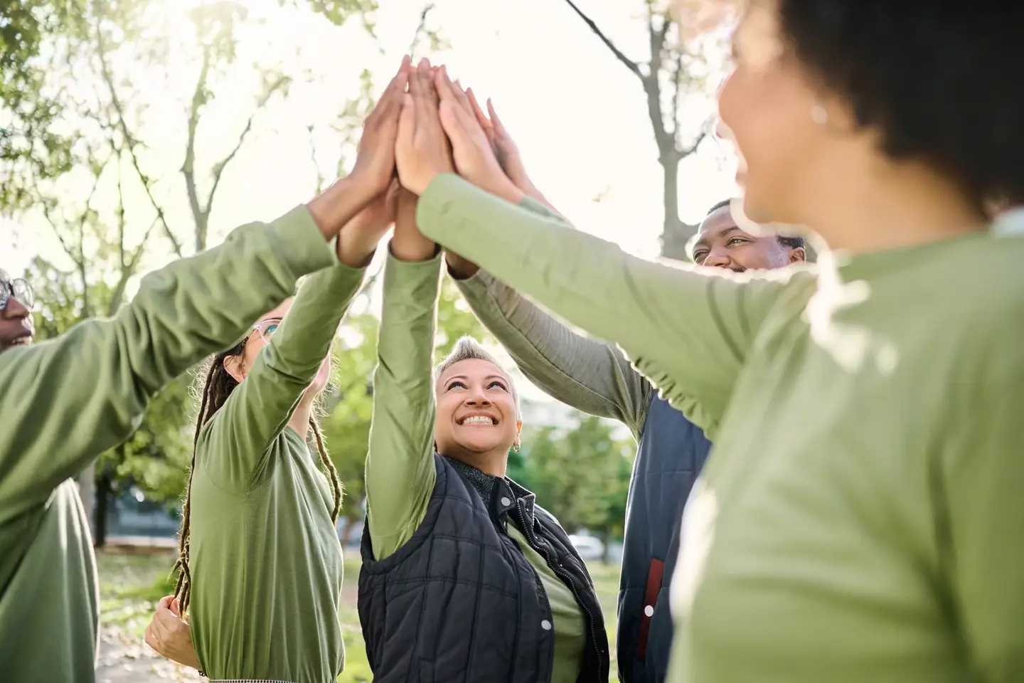 Group of volunteers high-five at a park clean up.