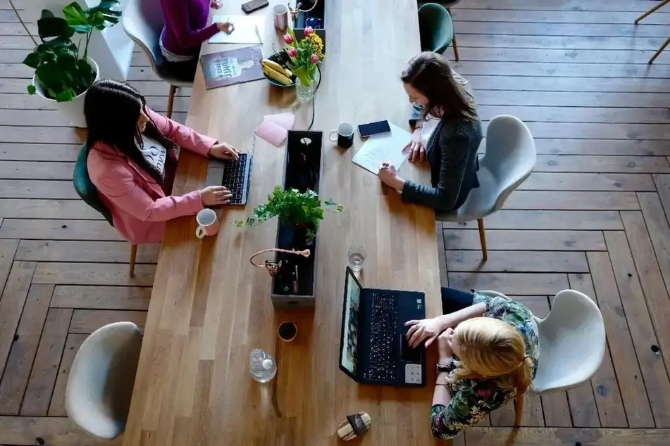 3 mulheres sentadas em uma mesa usando notebooks.
