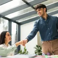 man shakes colleagues hands at an open-air office.